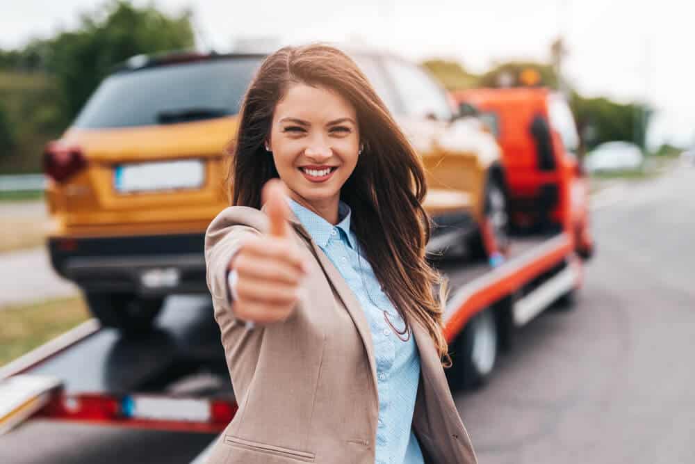 Elegant middle age business woman is happy and satisfied with fast and reliable towing service for help on the road.